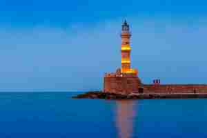 Foto vista panorâmica do farol no antigo porto de chania durante a hora do crepúsculo azul, creta, grécia