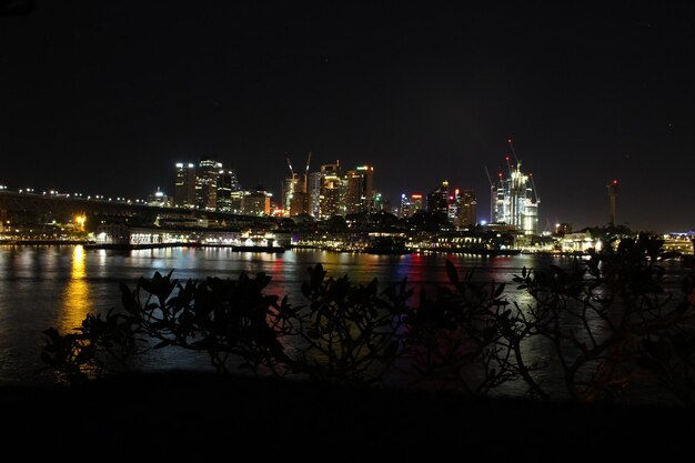 Foto vista panorâmica do lago pela cidade iluminada contra o céu à noite