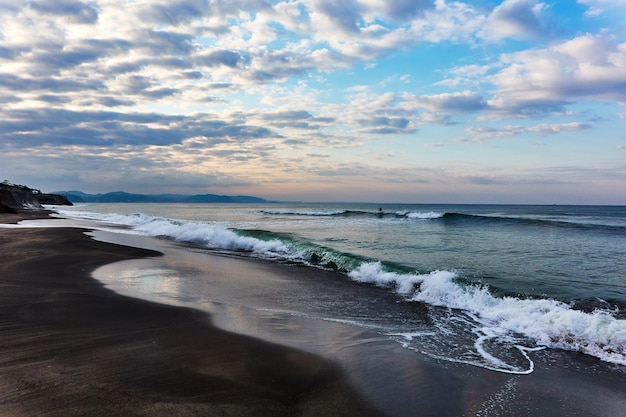 Vista panorâmica do mar com ondas batendo contra o céu dramático durante o nascer do sol
