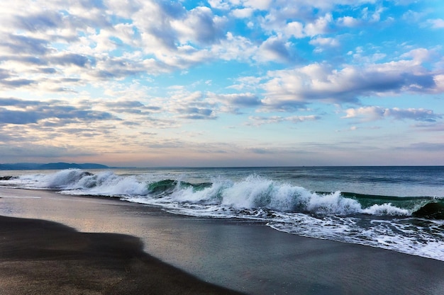 Vista panorâmica do mar com ondas quebrando contra o céu dramático durante o nascer do sol