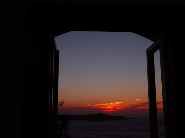 Vista panorâmica do mar contra o céu vista através da janela durante o pôr-do-sol