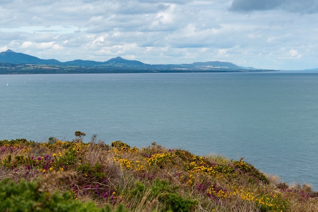 Vista panorâmica do mar da irlanda do farol principal de wicklow com montanhas de wicklow à distância.