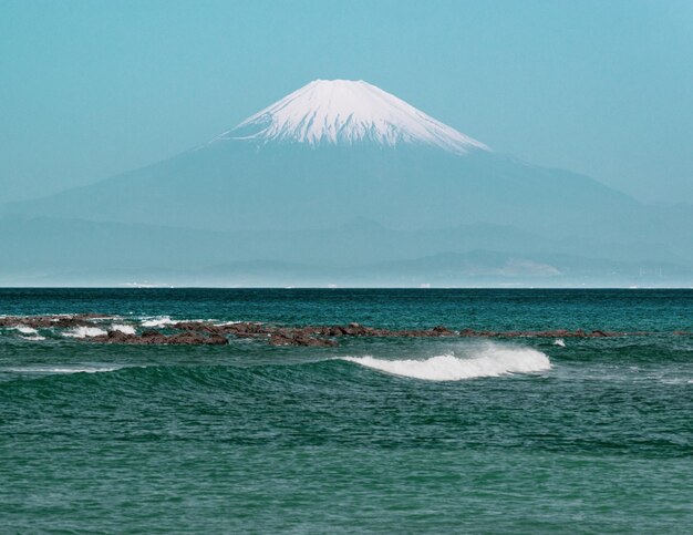 Foto vista panorâmica do oceano e do monte fuji contra o céu enevoado em uma manhã quente de verão