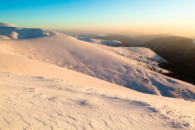 Vista panorâmica do pôr do sol nas colinas de inverno cobertas de neve e o sol se pondo acima