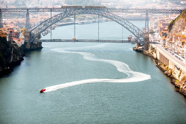 Foto vista panorâmica do rio douro com flutuadores de lancha e uma bela ponte de ferro na cidade do porto, portugal