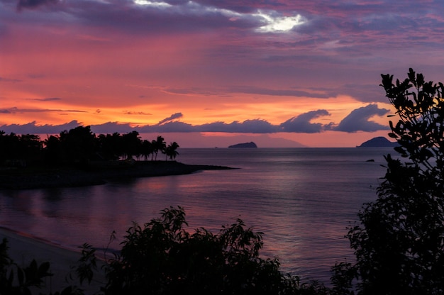 Vista panorâmica do rio em meio a árvores em silhueta contra o céu nublado durante o pôr do sol