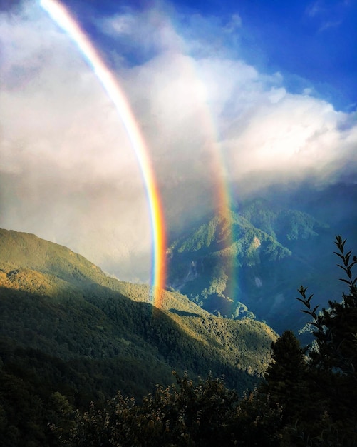 Foto vista panorámica del doble arco iris sobre la montaña contra el cielo