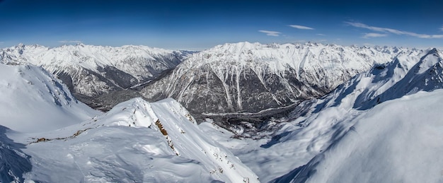 Vista panorâmica dos picos das montanhas nevadas nas nuvens, céu azul Cáucaso