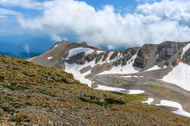 Vista panorámica escénica de un idílico paisaje de colinas onduladas con prados en flor y picos alpinos cubiertos de nieve en el fondo en un hermoso día soleado