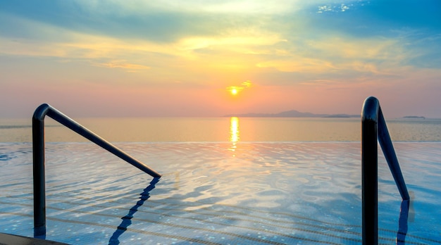 Vista panorámica espectacular de la piscina Infinity con escalera y hermosa puesta de sol en el mar a la hora del crepúsculo - Filtro Vintage