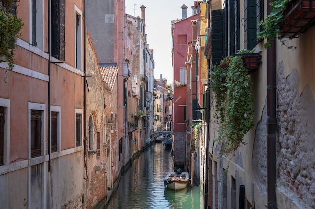 Vista panorámica del estrecho canal de Venecia con edificios históricos y barco desde el puente. Paisaje de día soleado de verano