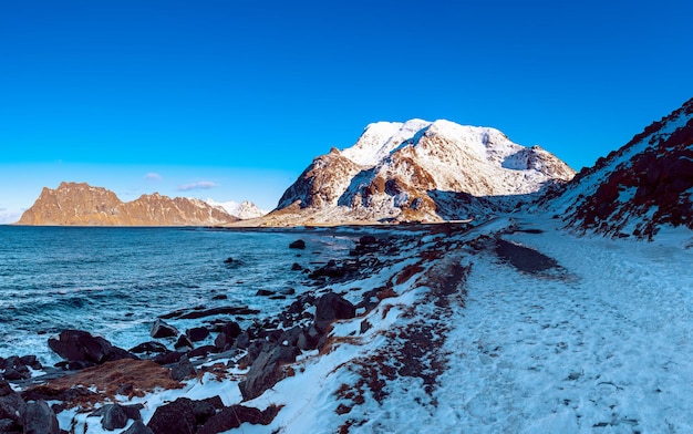 Vista panorámica del hermoso paisaje escandinavo de mar de invierno con cielo azul, montañas y nieve en las islas Lofoten en el norte de Noruega