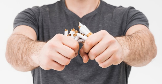 Foto vista panorámica del hombre sonriente rompiendo cigarrillos con las dos manos