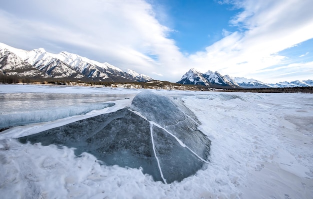 Vista panorámica del lago congelado por las montañas cubiertas de nieve contra el cielo