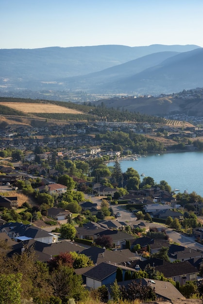 Vista panorámica del lago kalamalka y una pequeña ciudad durante el soleado amanecer de verano