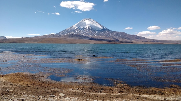 Vista panorámica del lago por las montañas cubiertas de nieve contra el cielo