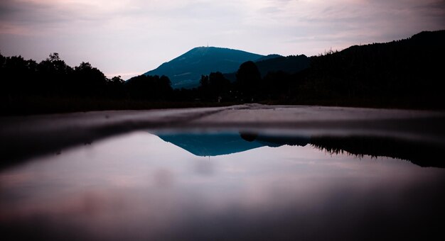 Foto vista panorámica del lago por la silueta de las montañas contra el cielo al atardecer