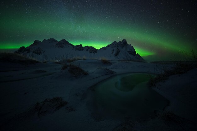 Vista panorámica de las montañas cubiertas de nieve contra el cielo con la aurora polar por la noche