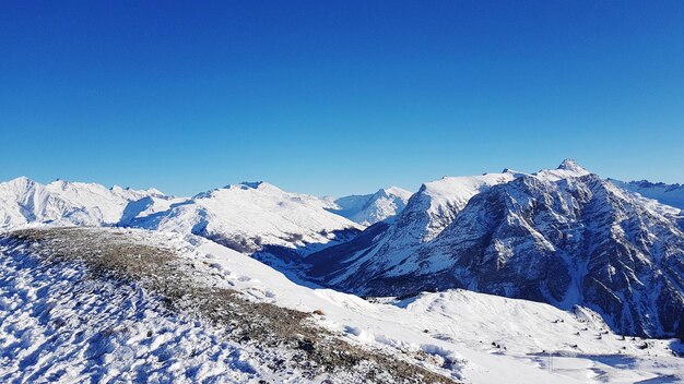 Foto una vista panorámica de las montañas cubiertas de nieve contra un cielo azul claro