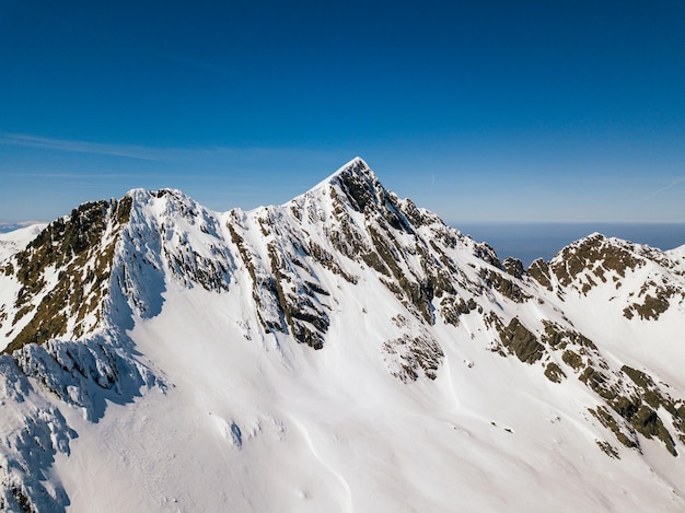 Foto una vista panorámica de las montañas cubiertas de nieve contra un cielo azul claro