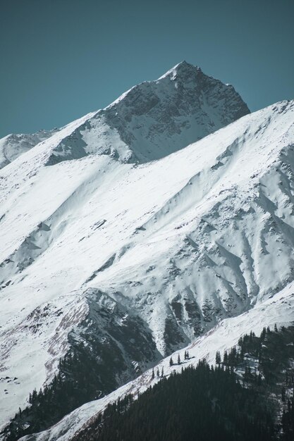 Foto una vista panorámica de las montañas cubiertas de nieve contra un cielo azul claro