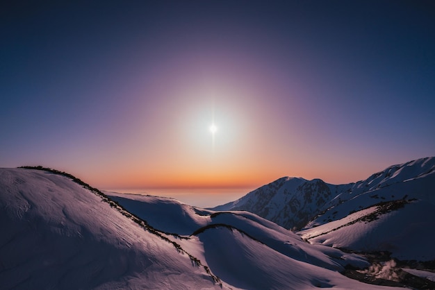 Vista panorámica de las montañas cubiertas de nieve contra un cielo despejado durante la puesta de sol