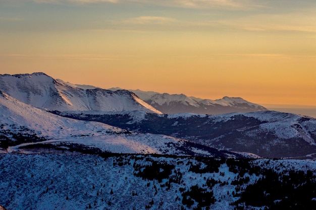 Vista panorámica de las montañas cubiertas de nieve contra el cielo durante la puesta de sol