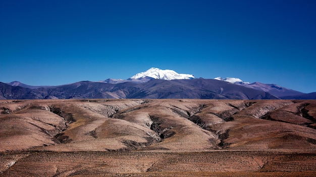 Foto una vista panorámica de las montañas cubiertas de nieve y el terreno escarpado en primer plano contra un cielo azul claro