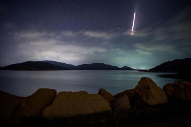 Vista panorámica de las montañas por el río contra el cielo nublado por la noche