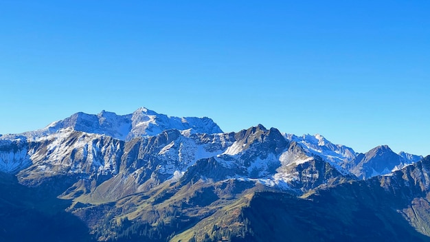 Vista panorámica de las montañas rocosas cubiertas de nieve contra un cielo azul