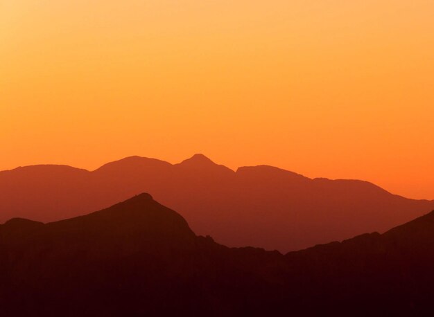 Vista panorámica de las montañas en silueta contra el cielo naranja