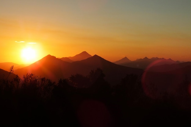 Foto vista panorámica de las montañas en silueta contra el cielo naranja