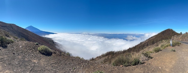 Vista panorámica de Una mujer que visita la isla de Tenerife toma fotografías sobre un mar de nubes