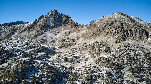 Vista panorámica de la nieve que cubre montañas rocosas bajo un cielo azul en un soleado día de invierno