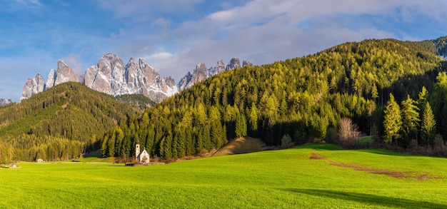 Foto vista panorámica del paisaje soleado con la iglesia de san juan contra las montañas geisler cubiertas de