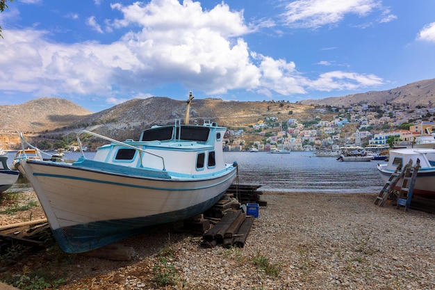 Vista panorámica del pequeño paraíso de Symi Island Village con pequeños barcos amarrados en la playa y casas coloridas ubicadas en las cimas de las montañas rocosas en la costa de Rodas Grecia