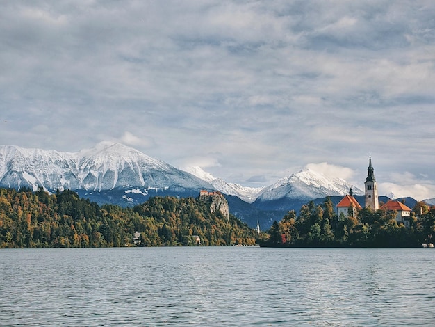 Vista panorámica de los picos de las montañas cubiertas de nieve contra el lago azul Bled, Eslovenia. Viajes de otoño