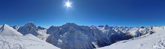 Vista panorámica de los picos de las montañas nevadas en las nubes del cielo azul del Cáucaso