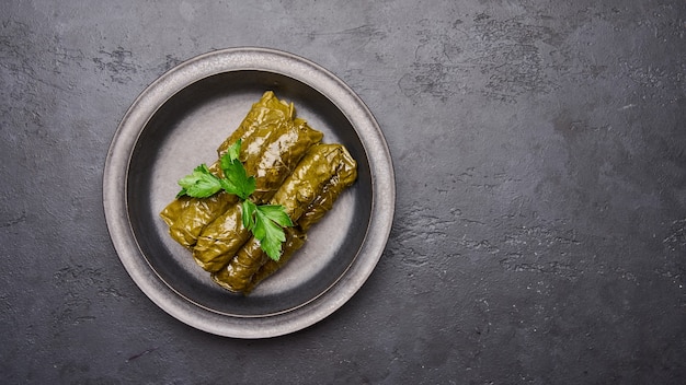 Vista panorámica plato tradicional de oriente medio dolma relleno de hojas de parra y perejil en placa negra