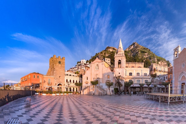 Vista panorámica de la plaza de la mañana Piazza IX Aprile con la iglesia de San Giuseppe, la torre del reloj y el volcán Etna en el fondo, Taormina, Sicilia, Italia