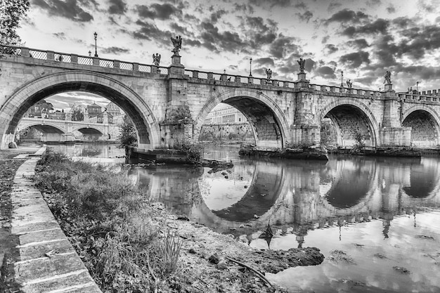 Vista panorámica del puente de Sant'Angelo con hermosos reflejos sobre el río Tíber en Roma, Italia