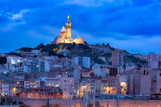 Vista panorámica del puerto viejo de la noche y la basílica de notre dame de la garde en el fondo del