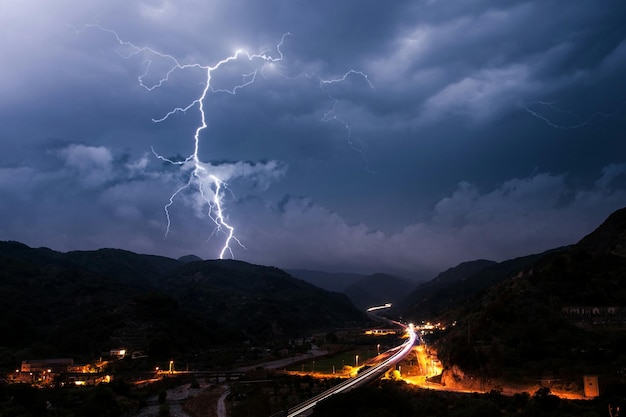 Vista panorámica del relámpago sobre la montaña por la ciudad iluminada