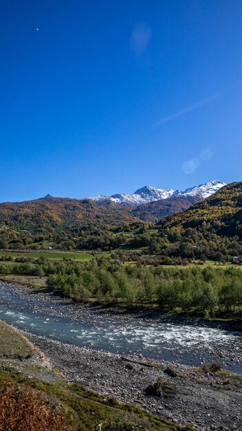 Una vista panorámica de un río tranquilo que fluye en primer plano con árboles de colores de otoño