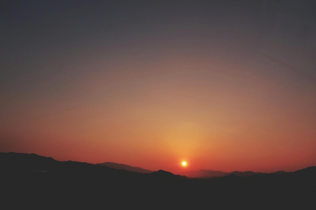 Vista panorámica de las siluetas de las montañas contra el sol durante la puesta de sol