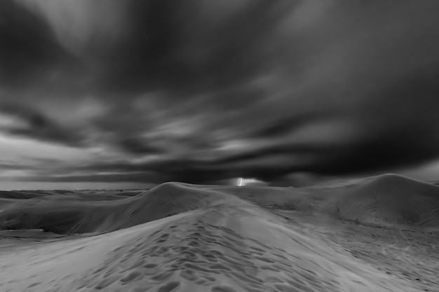 Foto vista panorámica de la tierra cubierta de nieve contra un cielo dramático