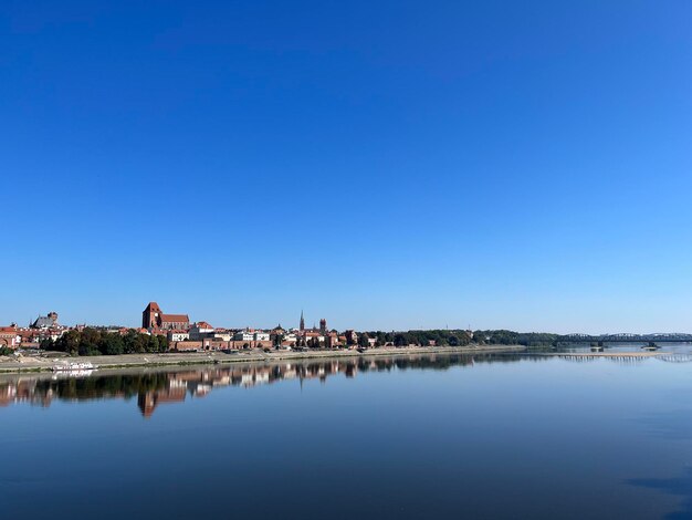 Foto vista panorámica de torun con el vistula en primer plano agua clara que refleja el cielo azul verano