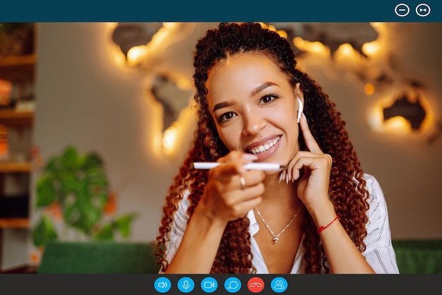 Vista de pantalla de retrato en la cabeza de una joven afroamericana sentada en casa hablando en video