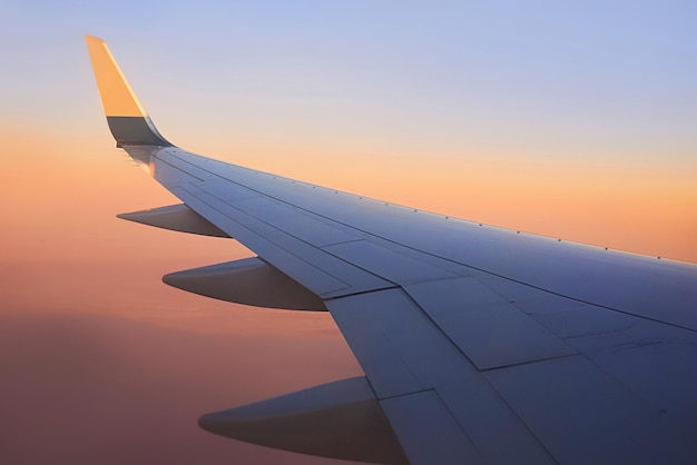 Vista para a asa do avião no céu durante o pôr do sol