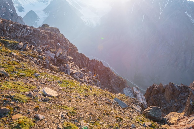 Vista para a montanha ensolarada do penhasco em altitude muito alta paisagem alpina cênica com belas rochas afiadas e couloirs e grande geleira à luz do sol belas paisagens na beira do abismo com pedras afiadas